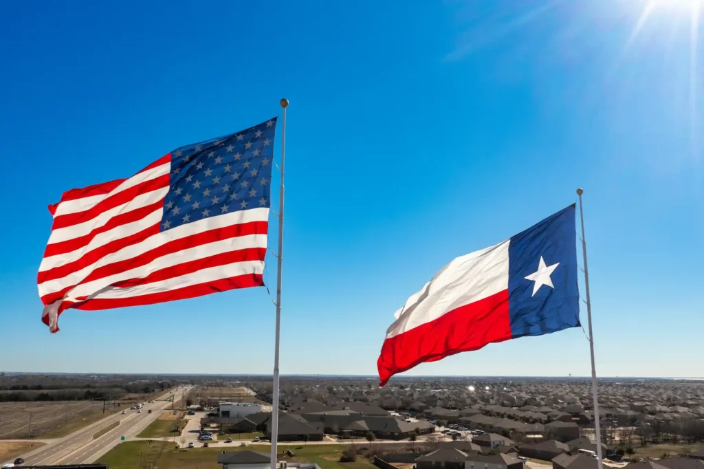 US flag and Texas flag flying against a sunny blue sky