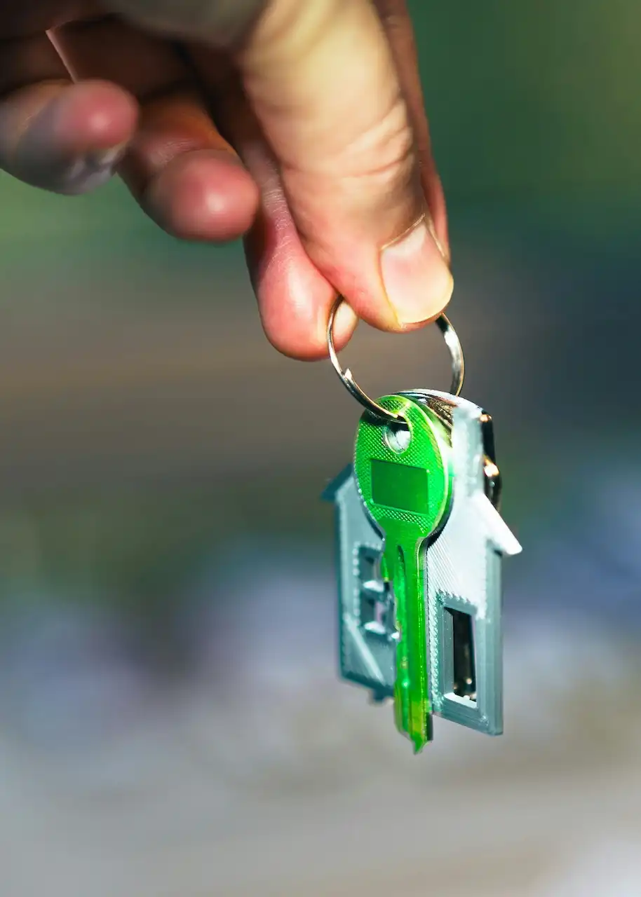 hand holding dangling green key on house keychain